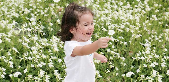 Sød lille pige rækker en blomst frem